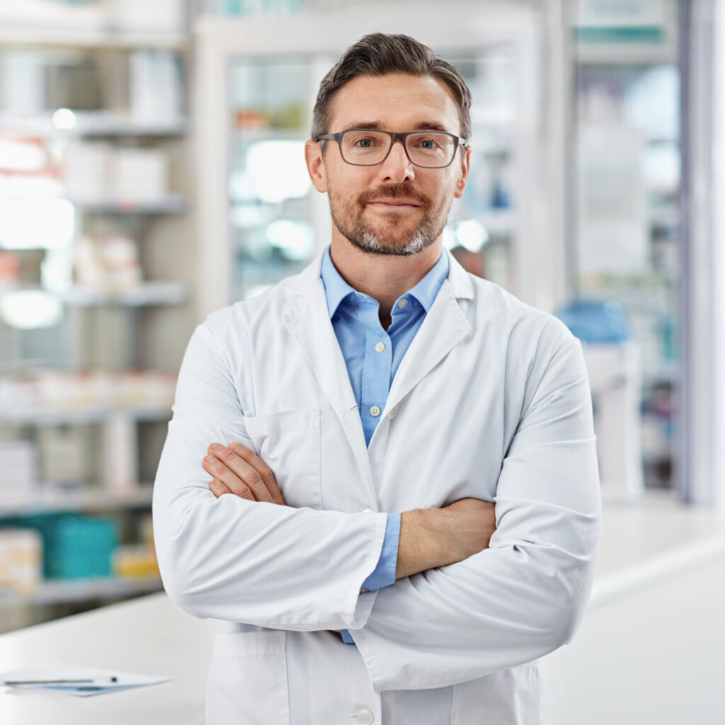 Portrait of a pharmacist standing with his arms crossed in a drugstore.
